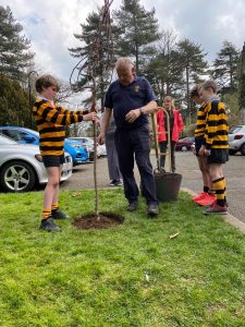 Children planting trees at Inchmarlo estate in a scenic outdoor setting.