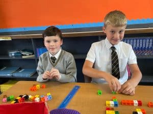 Two children playing with educational toys in a classroom setting.