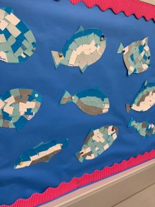 Colorful paper fish crafts displayed on a blue background.
