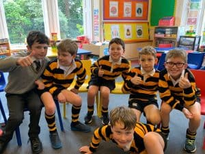 Group of children in school uniforms smiling in classroom.