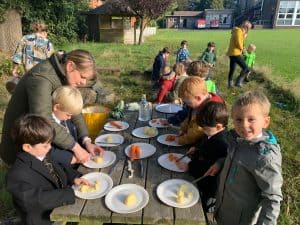 Children enjoying outdoor lunch at Inchmarlo school, engaging in outdoor activities and socializing on a sunny day.