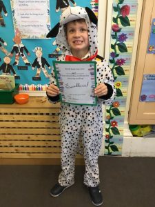 Young student in Dalmatian costume holding a certificate at Inchmarlo School, promoting learning and achievement.