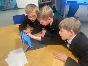 Three boys using a tablet in classroom setting at Inchmarlo School.