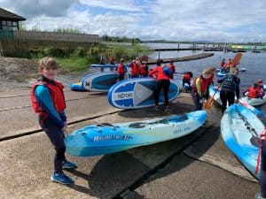 Children and adults preparing for paddleboarding by the water at Inchmarlo.