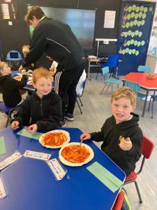 Children enjoying pizza and learning activities at Inchmarlo, a vibrant educational environment.