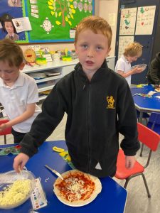 Young student cooking pasta in classroom.