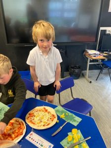Young boy smiling at Inchmarlo community event with pizza.