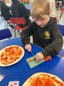 Young child making art with paint and paper at school.