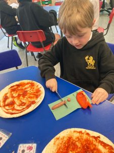 Young boy baking pizza at school activity.