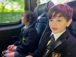 Young boys in school uniforms enjoying a trip on a bus.