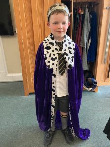 Young boy dressed as a royal with a purple cloak and leopard print collar at Inchmarlo.