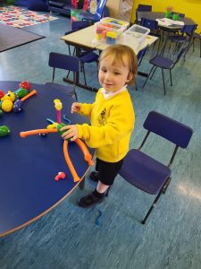 Young girl playing in nursery classroom with toys and colorful furniture in Inchmarlo childcare setting.