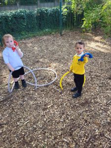 Two children playing with hoops on a woodland playground at Inchmarlo.