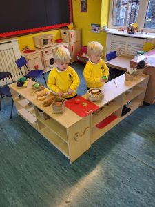 Two young children engaging in imaginative play in a colorful Inchmarlo nursery classroom.