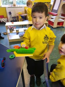 Young boy holding LEGO ship at Inchmarlo school.