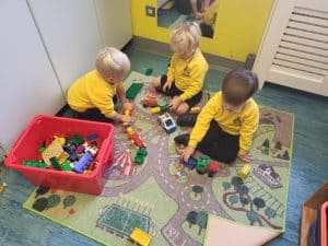 Children playing with building blocks in a colorful indoor play area.