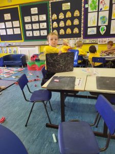 Young child working on a laptop in a vibrant classroom.