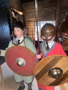 Children dressed as Vikings with shields and helmets at Inchmarlo historic site.