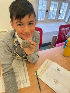 Happy boy holding a painted stone at Inchmarlo nursery.