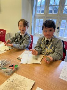 Two children reading books at a table in a bright room.