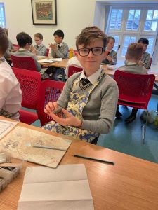 Young student holding a tablet in classroom with peers.
