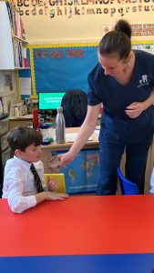 A teacher helps a young child with a book at Inchmarlo nursery, promoting early learning and development in a caring environment.