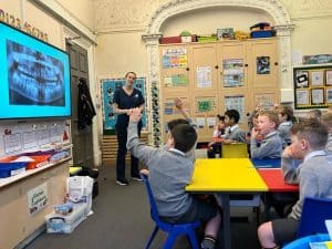 Young students engaging in classroom learning with a teacher and digital blackboard.