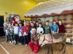 Group of children with a reindeer at Inchmarlo Christmas event, celebrating festive family activities.