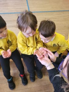 Three children in yellow uniforms holding hands at Inchmarlo preschool.
