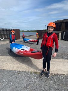 Girl in red kayaking gear with kayak on shore at Inchmarlo outdoor activities.