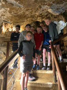 Group of kids exploring Inchmarlo caves in Scotland, adventure, outdoor activity, family fun, nature exploration.