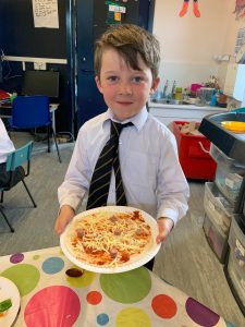 Young boy holding pizza at Inchmarlo School in Aberdeen, promoting quality education and vibrant school life.