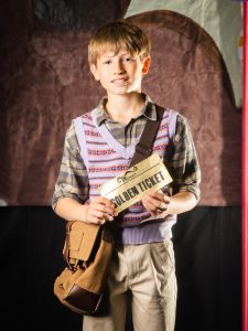 Young boy holding a "Golden Ticket" at Inchmarlo School event.