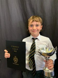Young student holding award and trophy at Inchmarlo School.