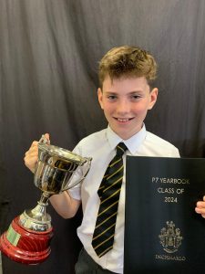Young student holding award trophy and certificate for 2024 class of at Inchmarlo.