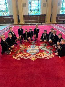 Young students gathered on a vibrant red carpet at Inchmarlo, engaging in a fun educational activity.