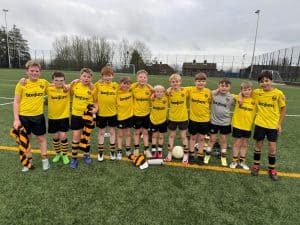 Young boys playing soccer in yellow jerseys on a field in Inchmarlo.