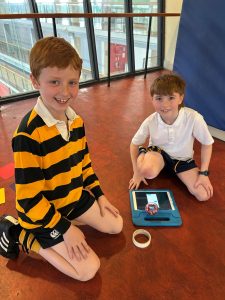 Two children playing with a tablet at Inchmarlo School, highlighting engaging learning experiences.