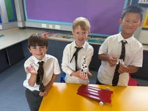 Three children playing with toy animals in a classroom setting.