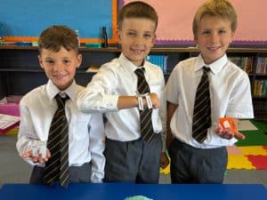 Happy schoolboys at Inchmarlo School with watches and snacks, enjoying a classroom activity.