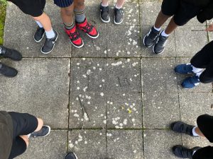 Students standing around painted numbers on outdoor pavement.