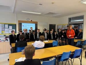 Students presenting in classroom setting with teacher and peers.