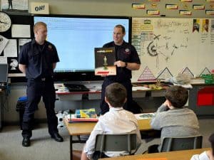 Two police officers giving a presentation to children in a classroom setting.