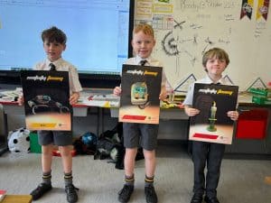 Three schoolboys holding award certificates in a classroom setting.