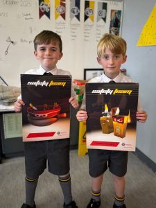 Two boys holding "Superdry" magazines in classroom.