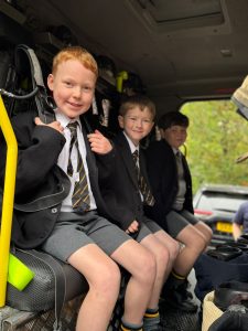 Smiling children in school uniforms sitting in a bus, ready for a school trip at Inchmarlo.