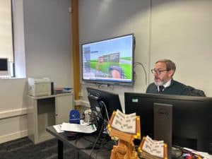 Modern office with computer and large screen.