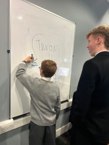 Young student writing on whiteboard at Inchmarlo educational event.