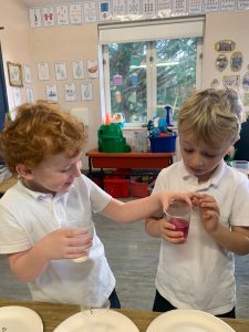Two children engaging in a classroom activity with colorful materials.