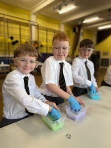 Three young boys in school uniforms engaging in a science activity at Inchmarlo.